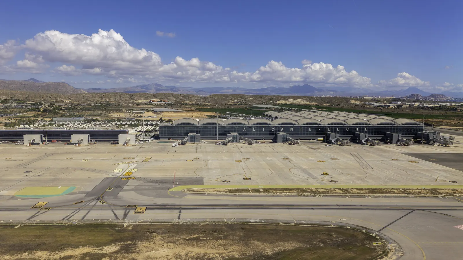 Terminal lotniska Alicante-Elche widziany od strony płyty postojowej, w tle góry